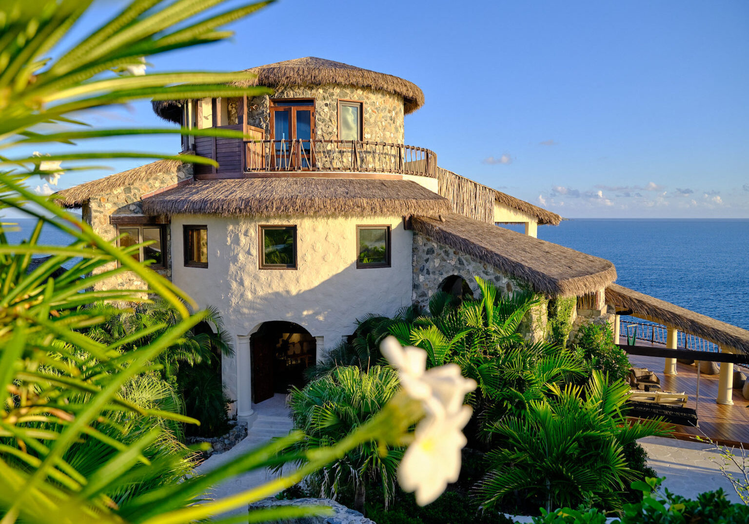Stone villa surrounded by greenery overlooking the ocean