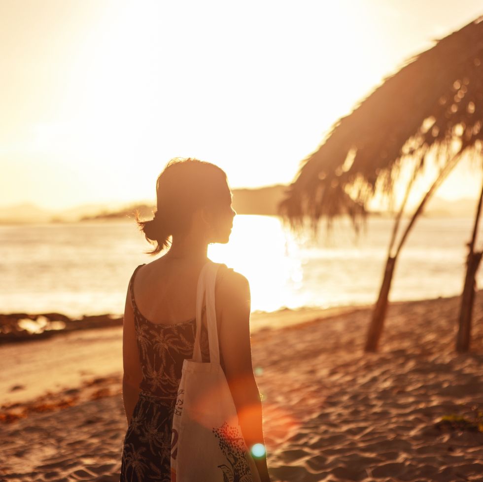 Woman walking on the beach at sunset