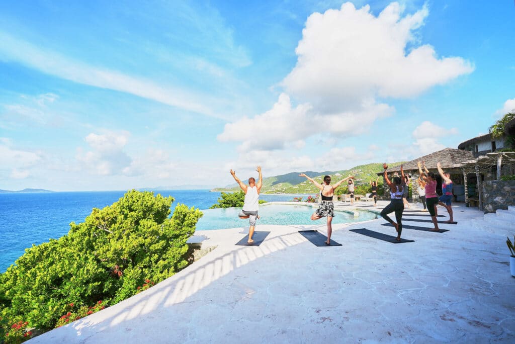 Group yoga session overlooking the ocean at a tropical wellness retreat.