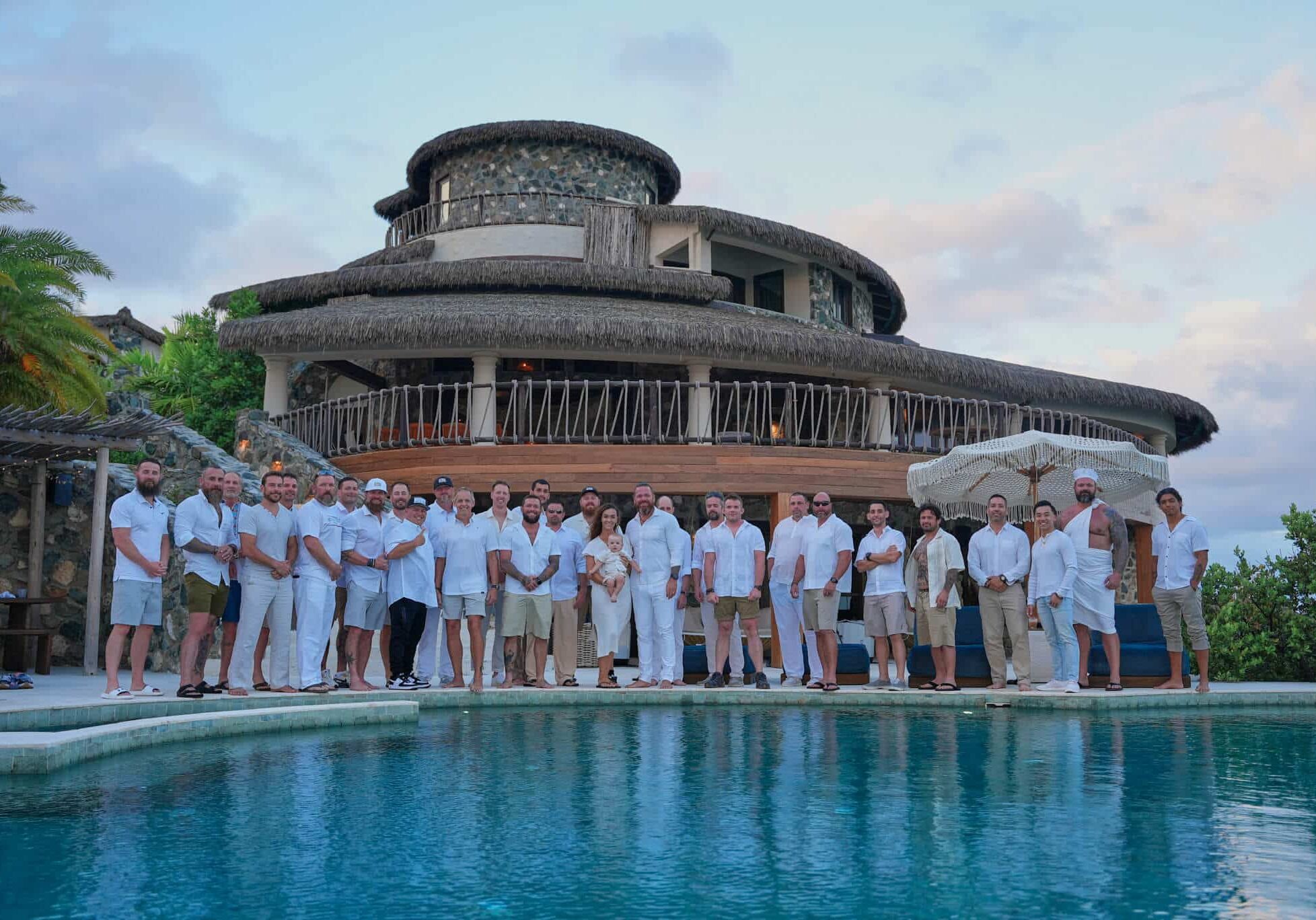 Veterans, first responders, and facilitators stand together beside the pool at The Aerial, BVI, representing community, restoration, and shared purpose.